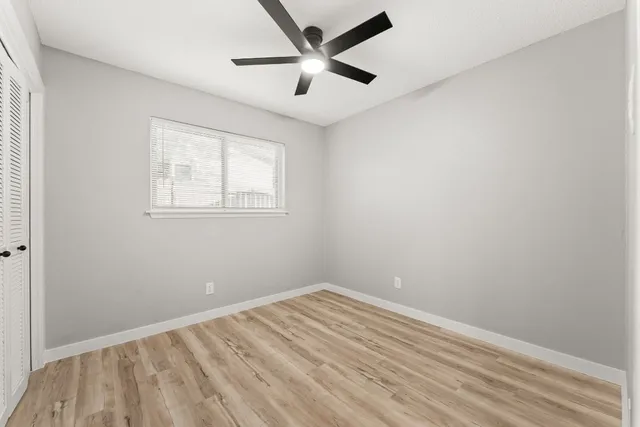 an empty room with a window and a fan