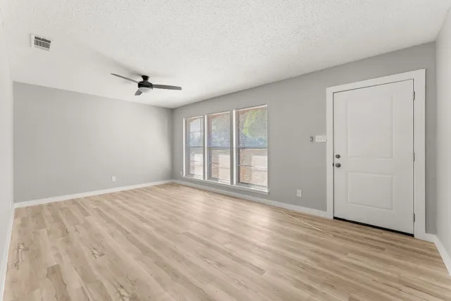a view of an empty room with a window and wooden floor