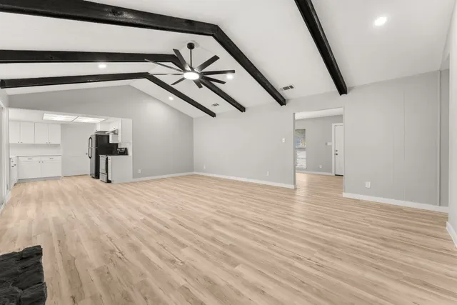a big room with wooden floor white walls and stairs