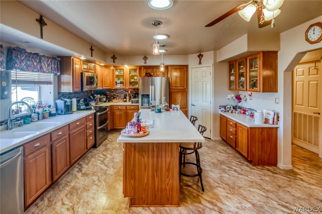 4150 Dragoon Road Golden Valley, AZ 86413 - Photo 19 of 49 a large kitchen with kitchen island a island wooden floors stainless steel appliances a sink and living room view