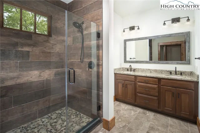 a bathroom with a granite countertop sink a mirror and a shower