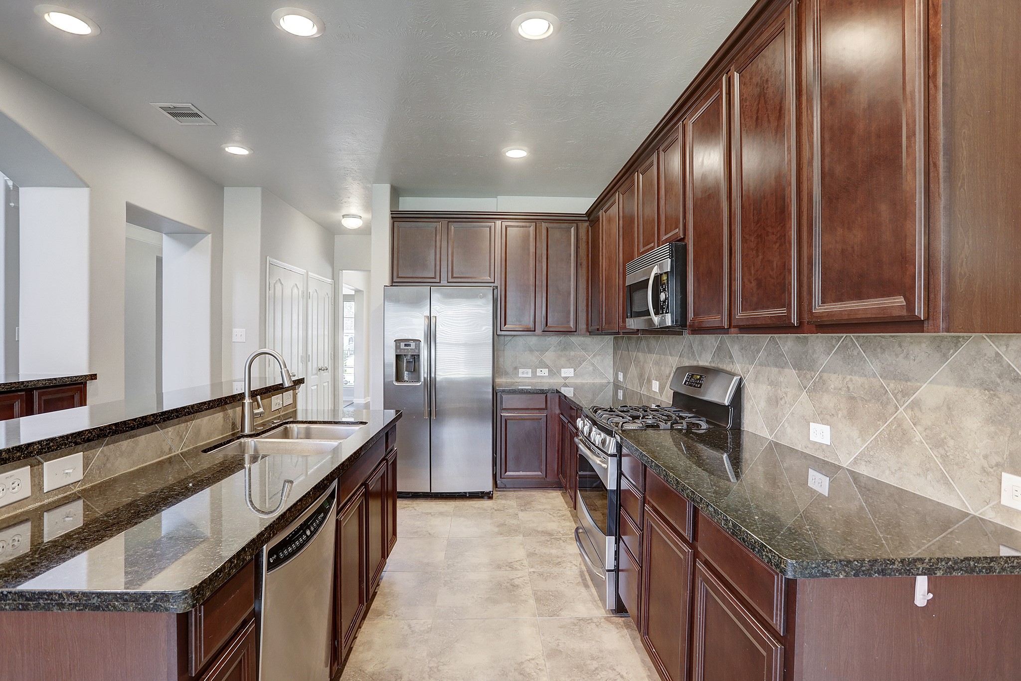 12331 Crescent Mountain Lane Humble, TX 77346 - Photo 16 of 34 a kitchen with granite countertop stainless steel appliances a sink a stove and a refrigerator