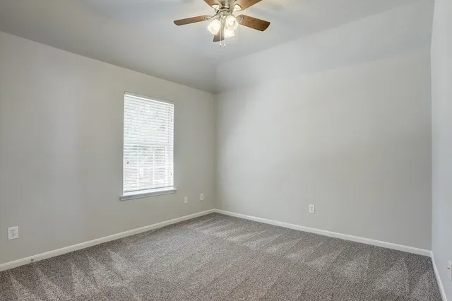 an empty room with a window and a fan