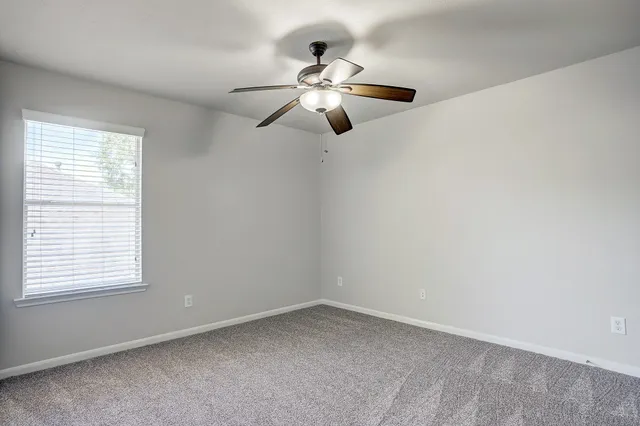 an empty room with a window and a fan