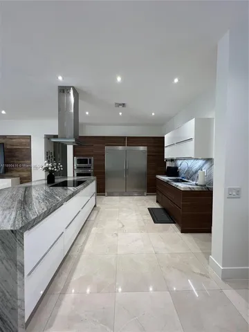a large white kitchen with a large counter top and stainless steel appliances