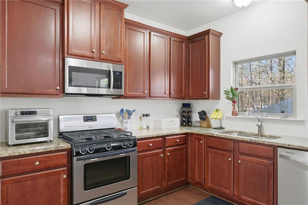 246 Manous Way Canton, GA 30115 - Photo 3 of 38 a kitchen with granite countertop wooden cabinets and a stove top oven