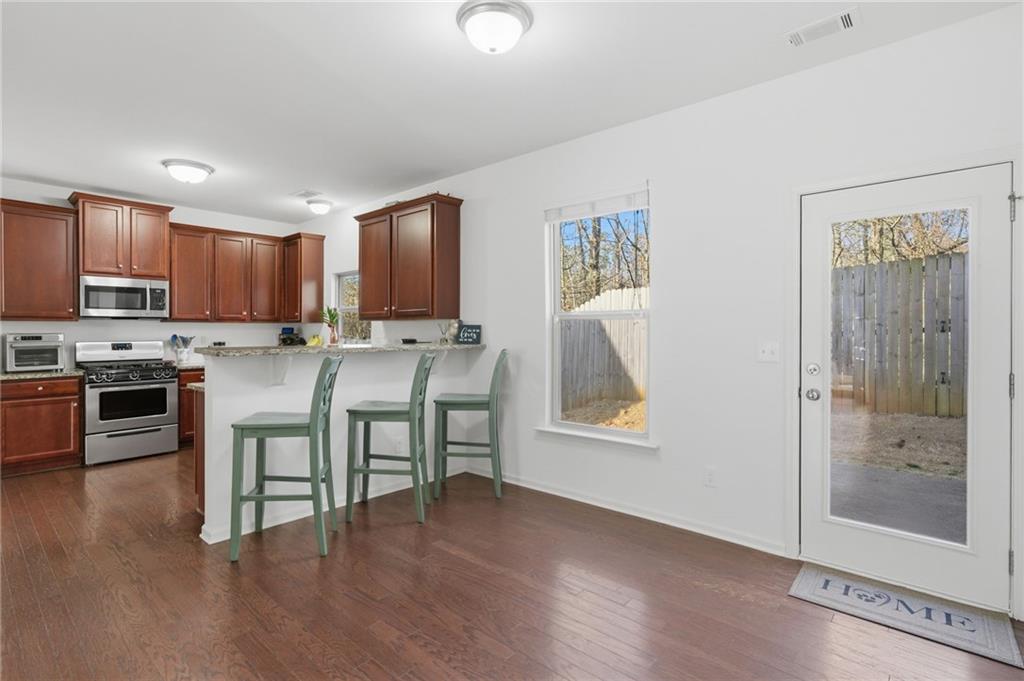 246 Manous Way Canton, GA 30115 - Photo 5 of 38 a kitchen with stainless steel appliances granite countertop a stove top oven a sink and dishwasher with wooden floor