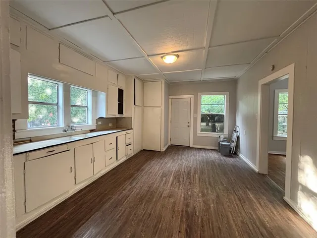 a large kitchen with cabinets wooden floor and a window