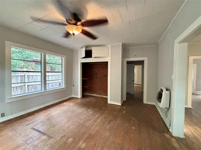 a view of an empty room with a window and wooden floor
