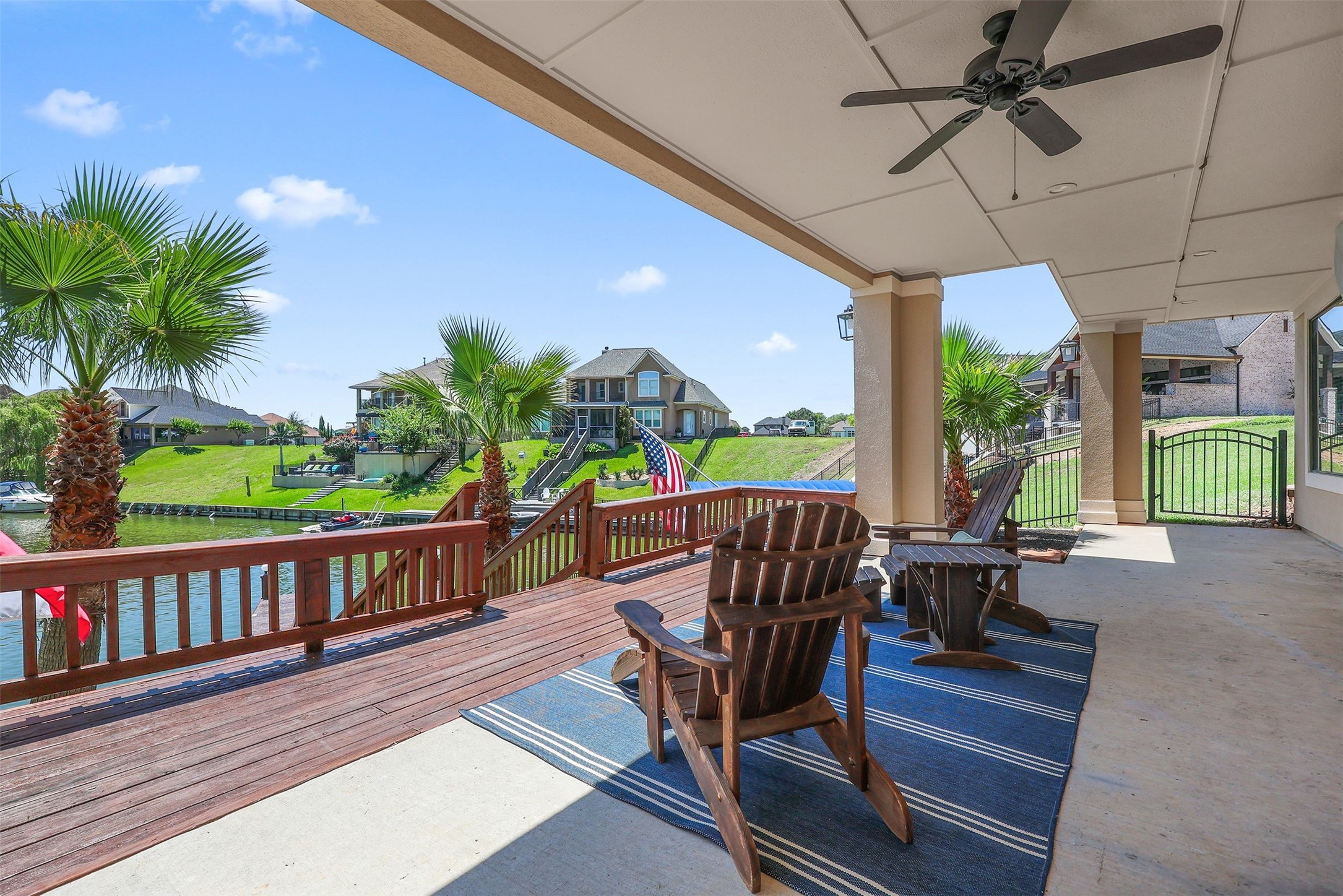 10896 Decatur Street Willis, TX 77318 - Photo 46 of 50 Discover the ultimate waterfront retreat with a spacious patio, featuring a ceiling fan and cozy wooden chairs on a rug, all overlooking a tranquil canal and lush greenery—ideal for relaxation and outdoor entertaining.