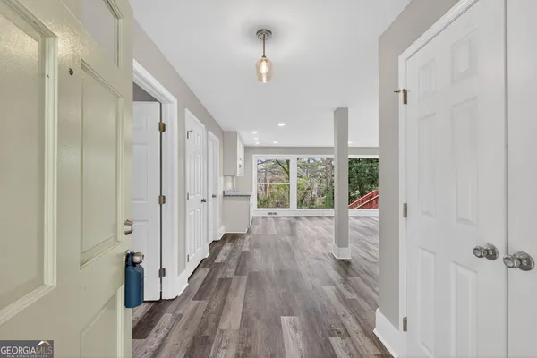 a view of a hallway with wooden floor and a bathroom