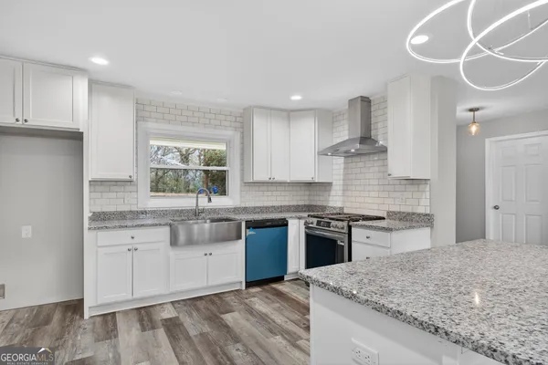 a kitchen with stainless steel appliances granite countertop hardwood floor sink stove and granite counter top