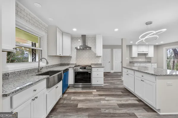 a large kitchen with granite countertop a sink and dishwasher a stove top oven with wooden floor