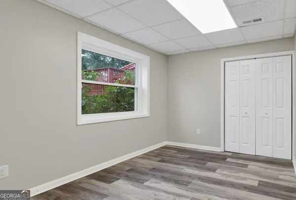 a view of an empty room with wooden floor and a window