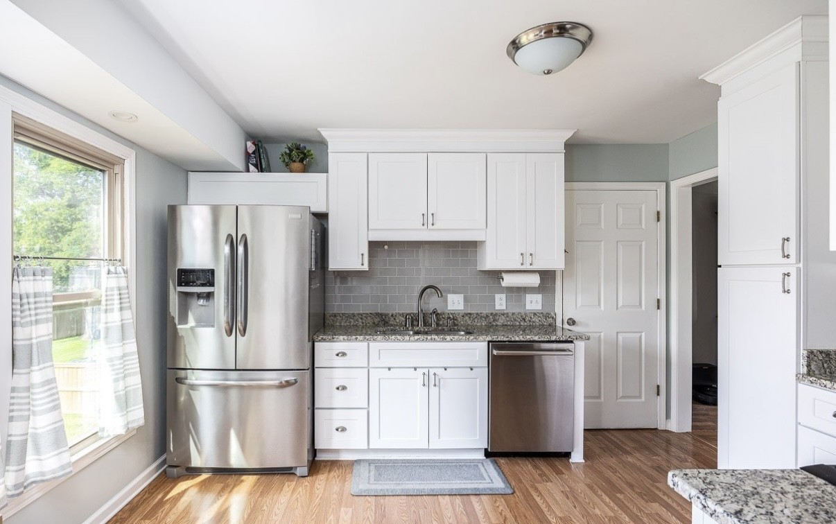 705 Baugh Road Nashville, TN 37221 - Photo 10 of 31 a kitchen with a refrigerator a stove a sink and white cabinets with wooden floor