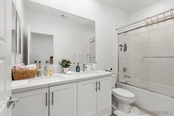 a bathroom with a double vanity sink toilet mirror and shower
