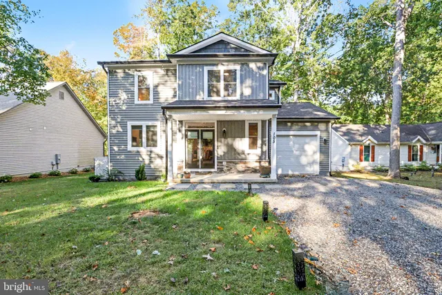 a view of a house with a yard plants and large tree