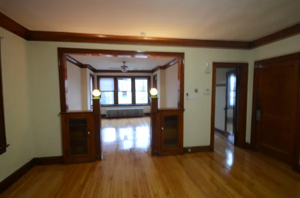 a view of empty room with wooden floor and fan