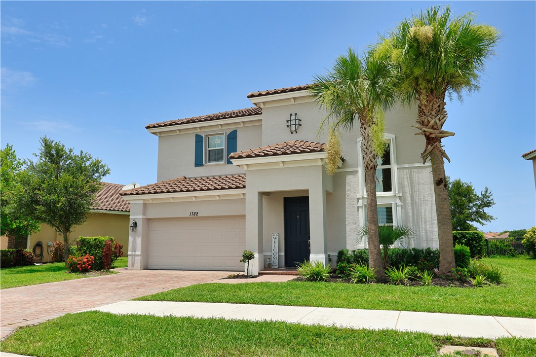 1782 Berkshire Circle Southwest Vero Beach, FL 32968 - Photo 1 of 35 a front view of a house with a garden and yard