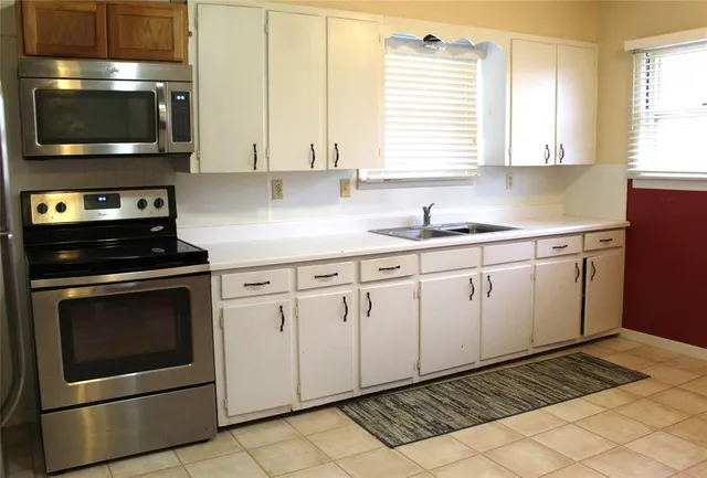 a kitchen with granite countertop white cabinets stainless steel appliances and window