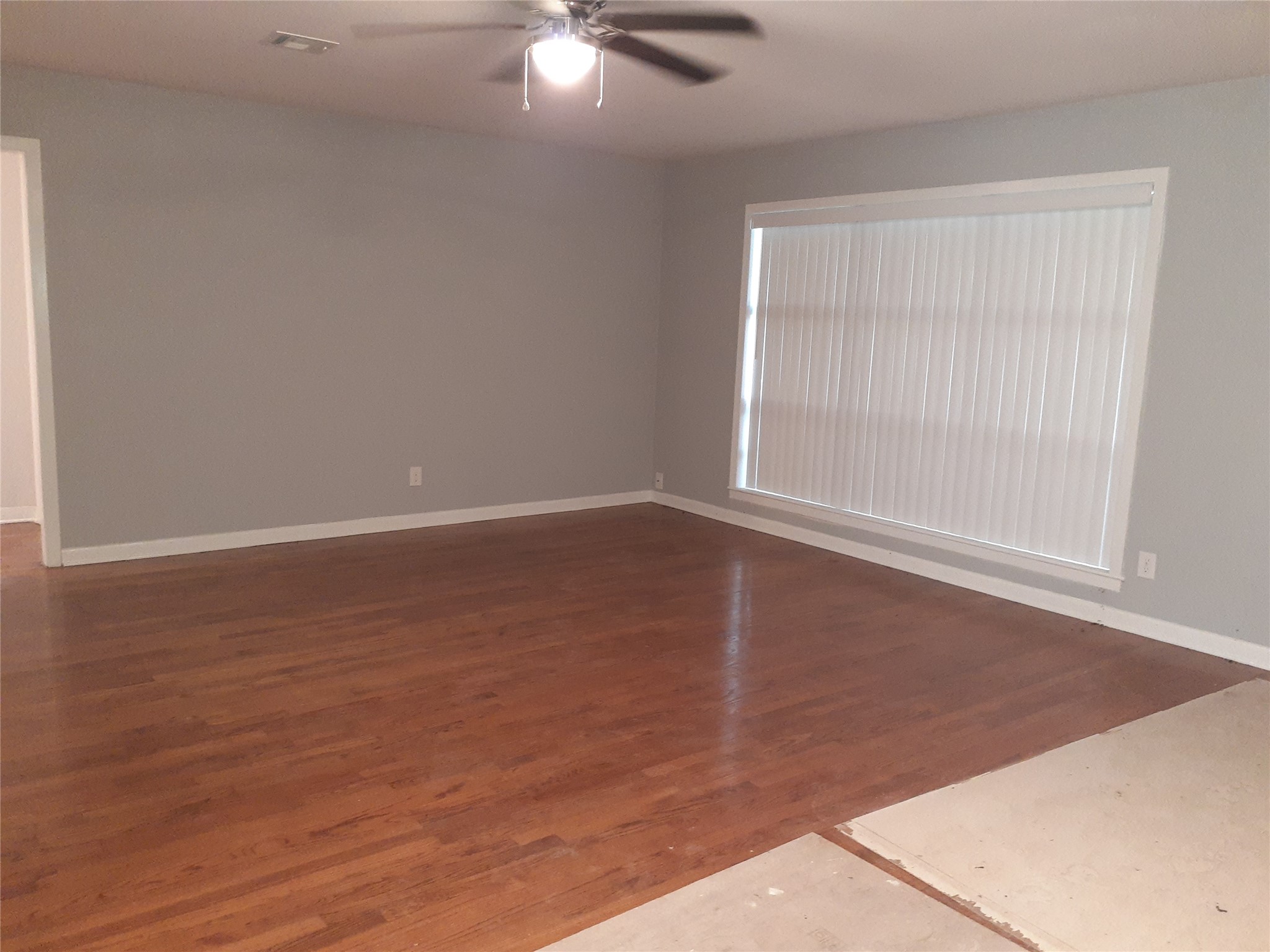 1213 Tobola Street Rosenberg, TX 77471 - Photo 3 of 8 an empty room with wooden floor fan and windows