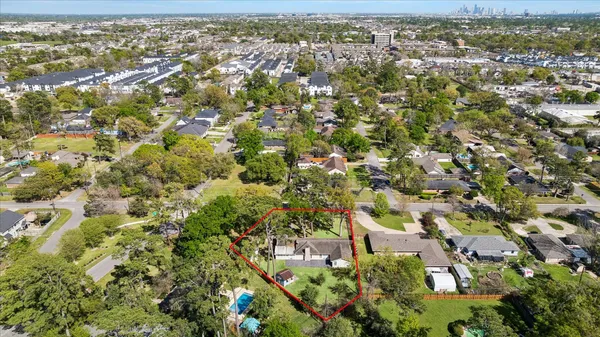 an aerial view of residential houses with outdoor space and trees