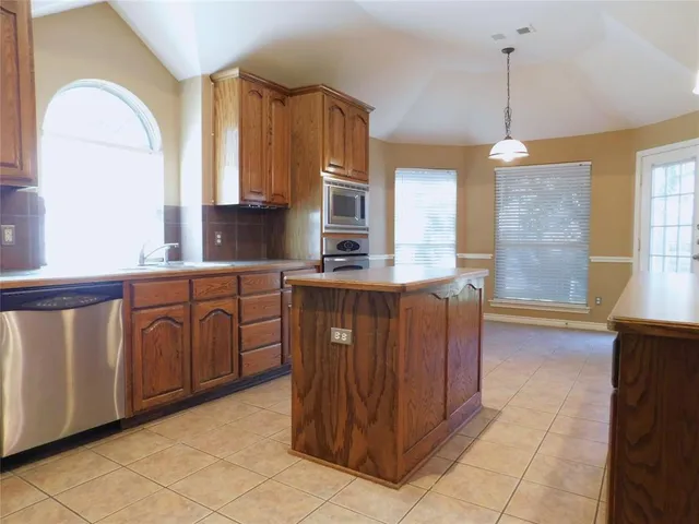 a kitchen with kitchen island granite countertop a stove a sink dishwasher and cabinets with wooden floor