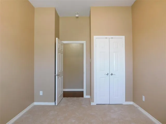 a view of an empty room with closet and a bathroom