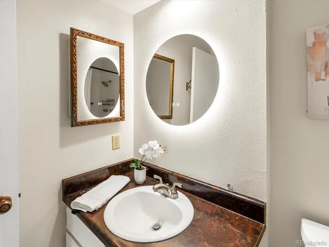 a bathroom with a granite countertop sink toilet and a mirror