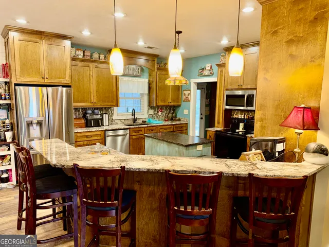 a kitchen with granite countertop a table chairs stove and refrigerator