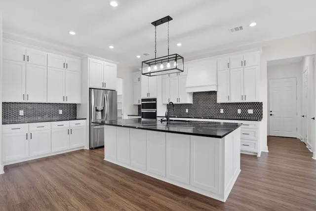 a kitchen with stainless steel appliances granite countertop a sink cabinets and wooden floor