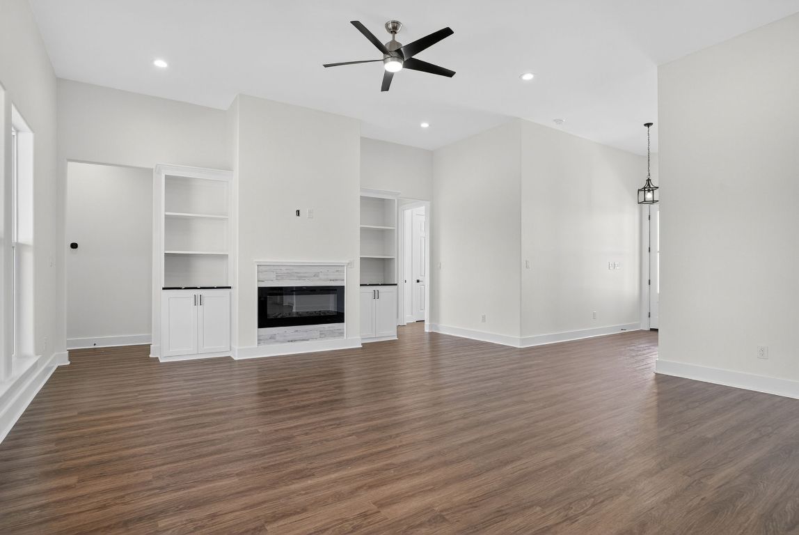 1035 Brandywine Court Elgin, TX 78621 - Photo 10 of 26 an empty room with wooden floor a ceiling fan a fireplace and windows