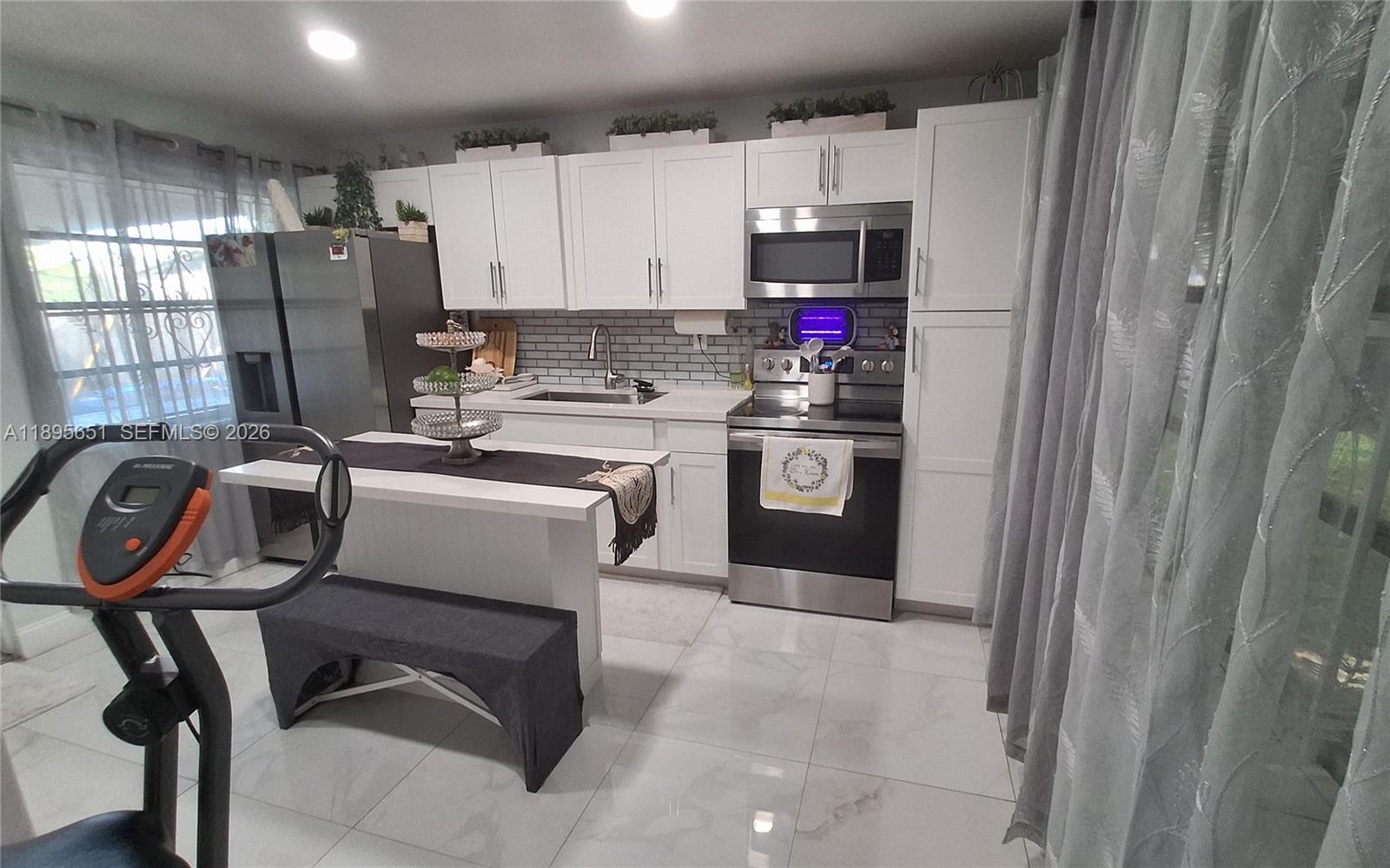 10305 Southwest 149th Terrace Miami, FL 33176 - Photo 20 of 58 a kitchen with kitchen island a stove a refrigerator and a refrigerator