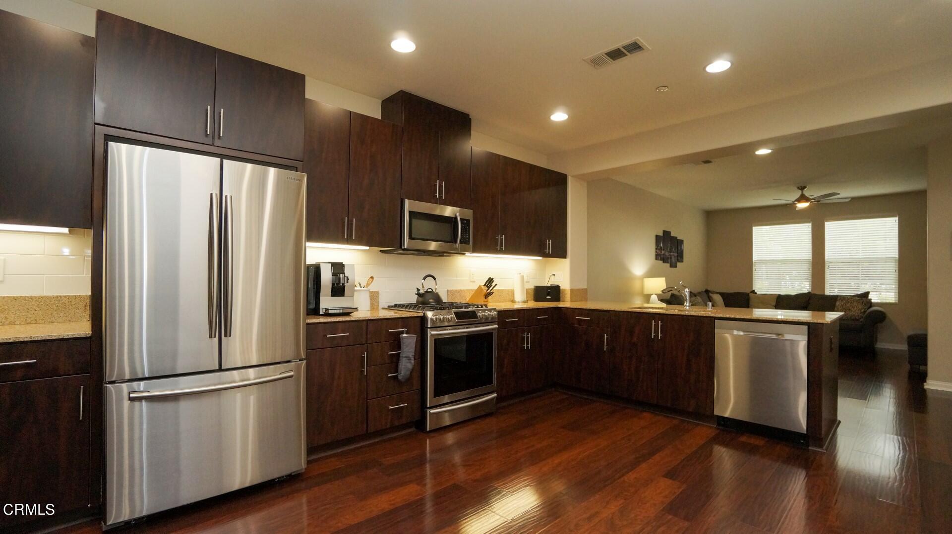 729 Forest Park Boulevard Oxnard, CA 93036 - Photo 6 of 27 a kitchen with stainless steel appliances granite countertop a refrigerator a stove top oven a sink and dishwasher with wooden floor