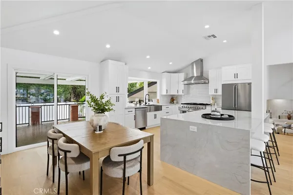 a kitchen with stainless steel appliances granite countertop a stove a refrigerator a kitchen island a dining table and chairs