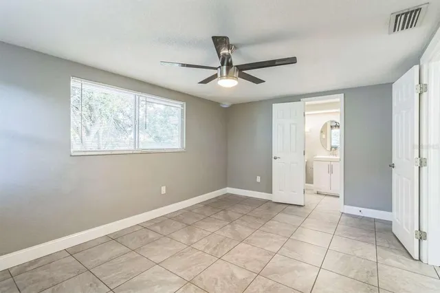 a view of an empty room with window and chandelier fan