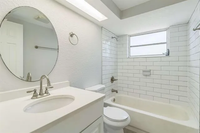 a bathroom with a bathtub sink vanity mirror and toilet