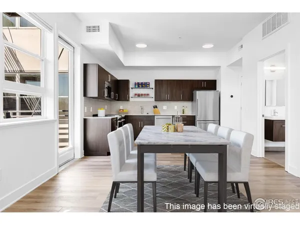 a dining room with stainless steel appliances kitchen island granite countertop a dining table chairs and a refrigerator