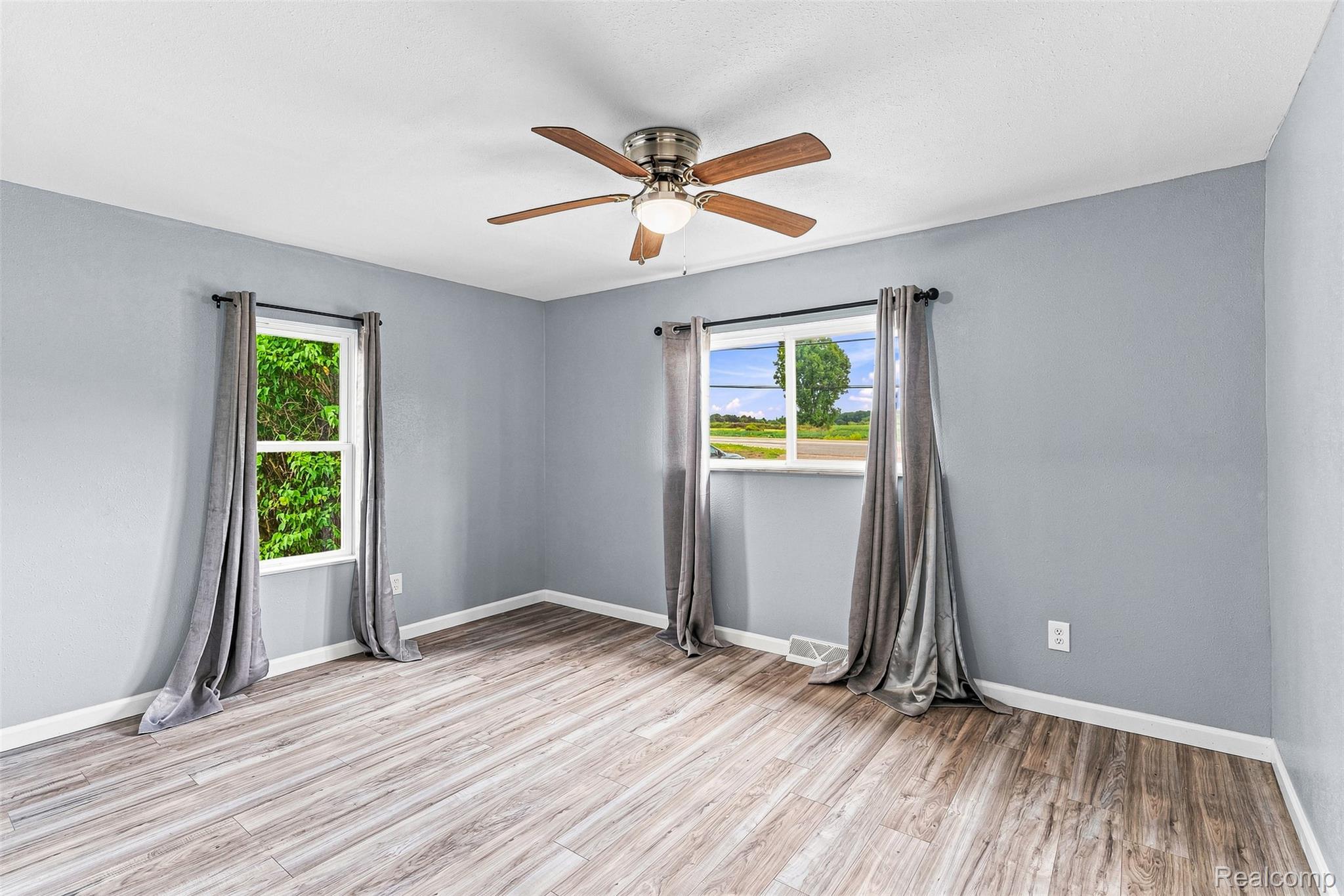 6163 North State Road Davison, MI 48423 - Photo 27 of 45 Light wood-finish flooring, light gray walls, two windows, and a ceiling fan with light fixture