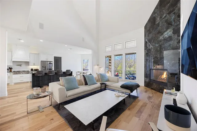 a living room with furniture a rug kitchen view and a large window