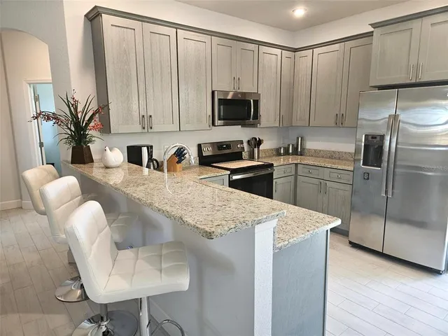 a kitchen with stainless steel appliances granite countertop a sink a microwave a refrigerator and white cabinets