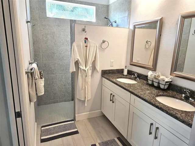 a bathroom with a granite countertop shower sink and mirror