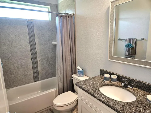 a bathroom with a granite countertop sink toilet a mirror and shower