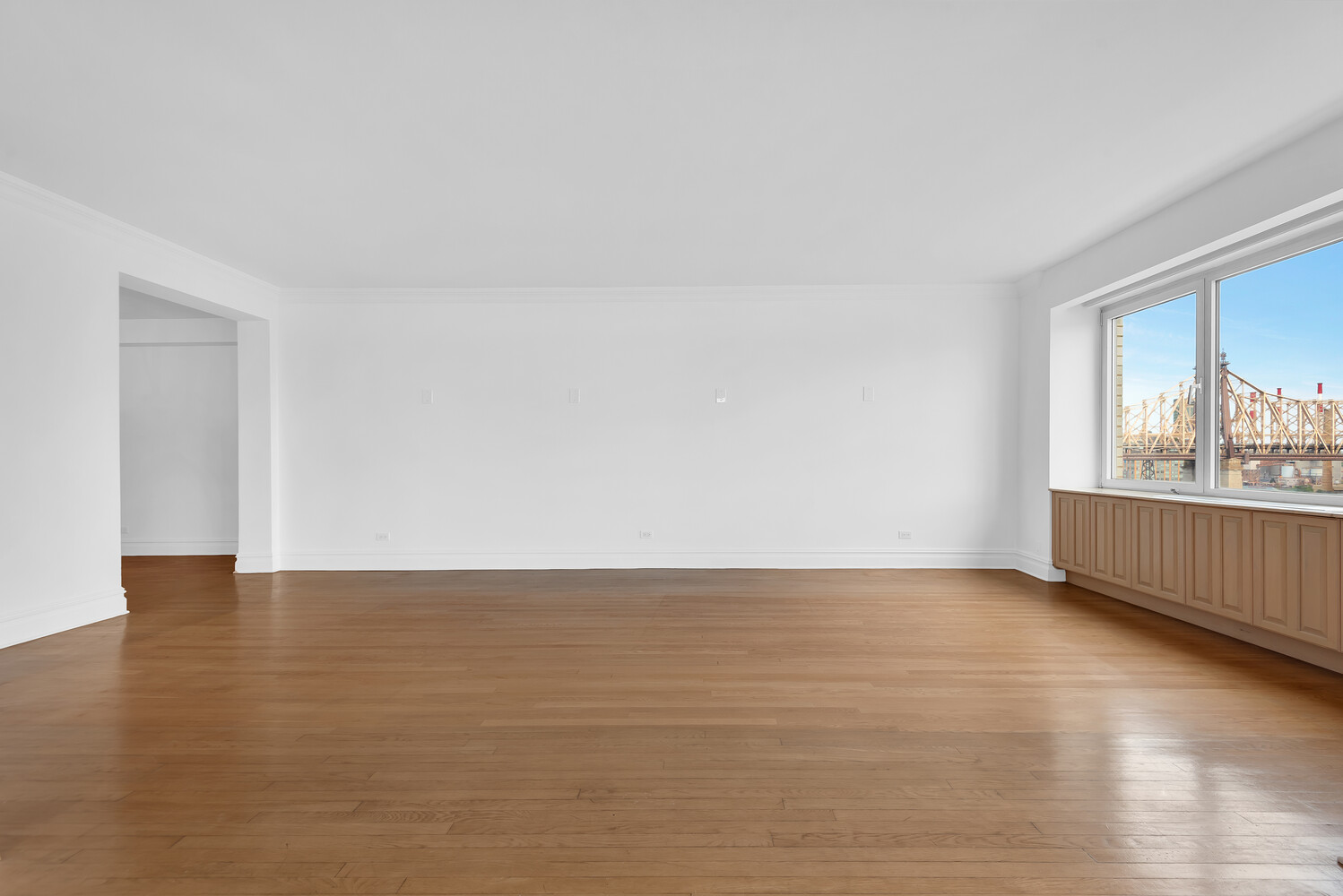 45 Sutton Place South, Unit 14F Manhattan, NY 10022 - Photo 3 of 20 a view of an empty room with a window and wooden floor