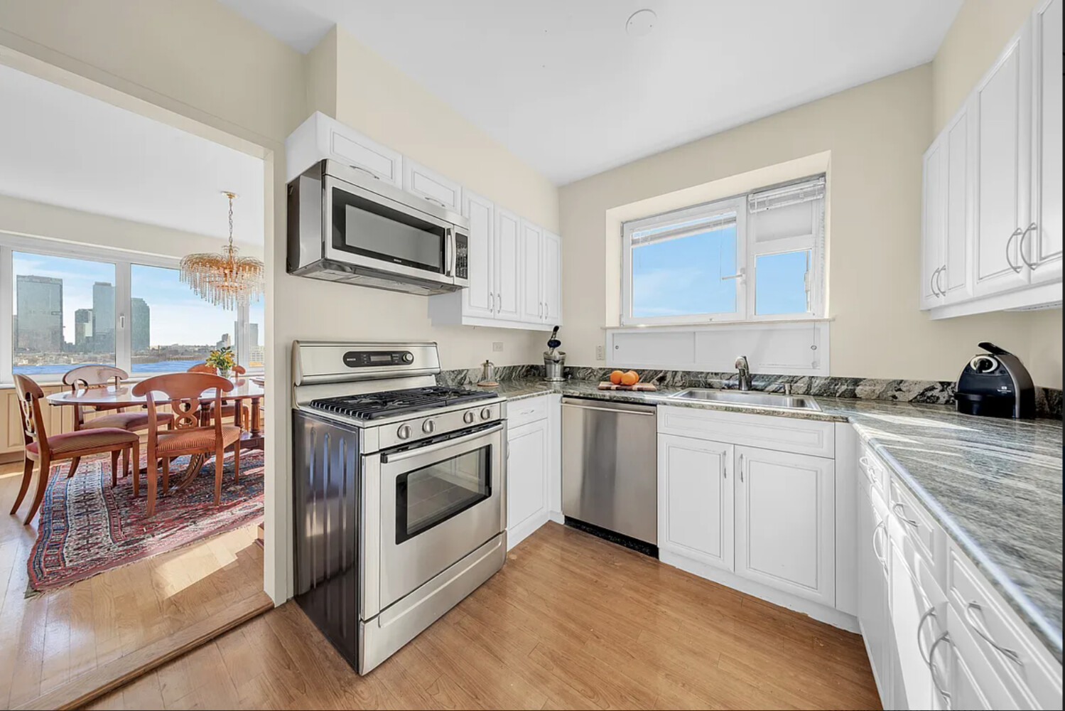 45 Sutton Place South, Unit 14F Manhattan, NY 10022 - Photo 4 of 20 a kitchen with granite countertop a stove top oven and cabinets