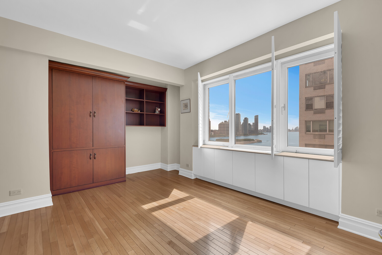 45 Sutton Place South, Unit 14F Manhattan, NY 10022 - Photo 9 of 20 a view of an empty room with wooden floor and a window
