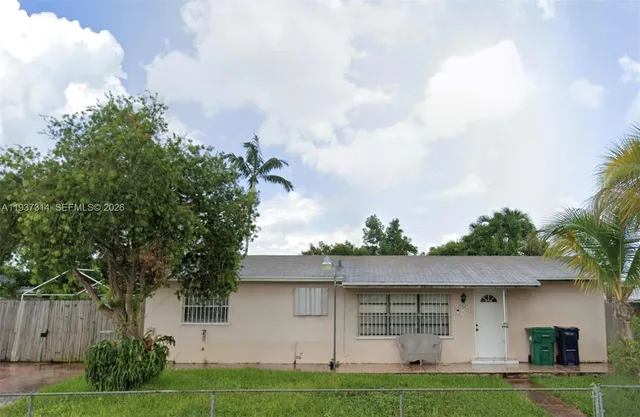 a front view of a house with a garden and trees