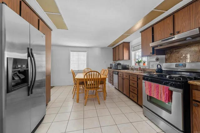 a kitchen with stainless steel appliances granite countertop a stove a sink dishwasher and a refrigerator