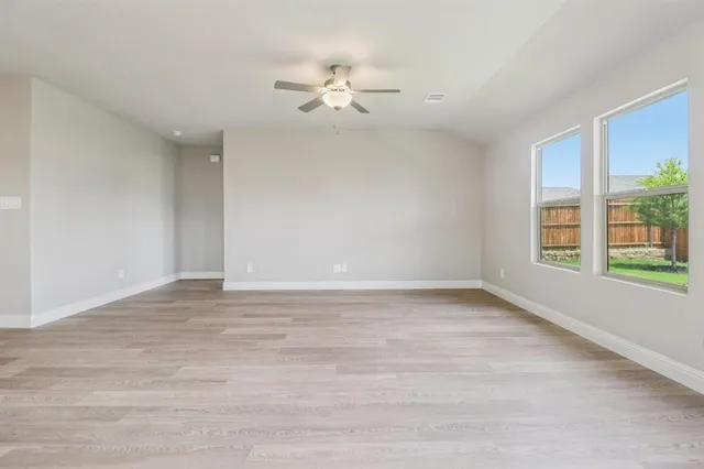 a view of an empty room with window and wooden floor