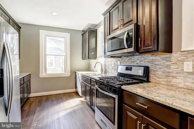 a kitchen with stainless steel appliances granite countertop a stove a sink and a microwave